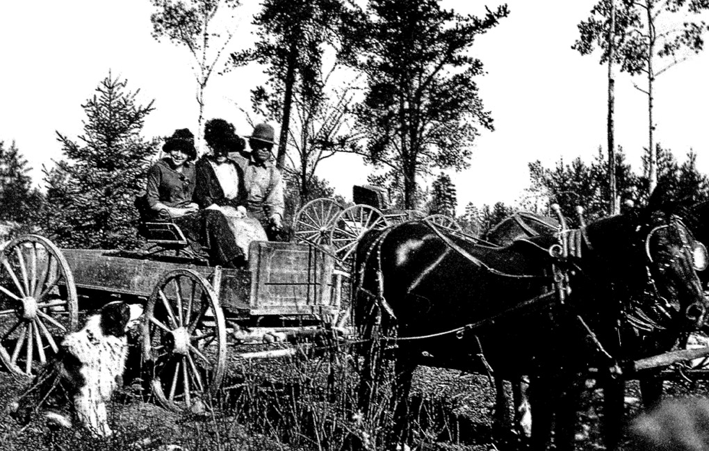 Image of early settlers in a wooden horse drawn wagon